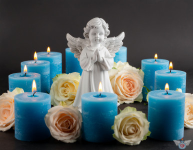 Ein Engel inmitten brennender blauer Kerzen und bunten Rosen auf einem dunklen Hintergrund. Symbol für Gedenken, Trauer und Frieden.